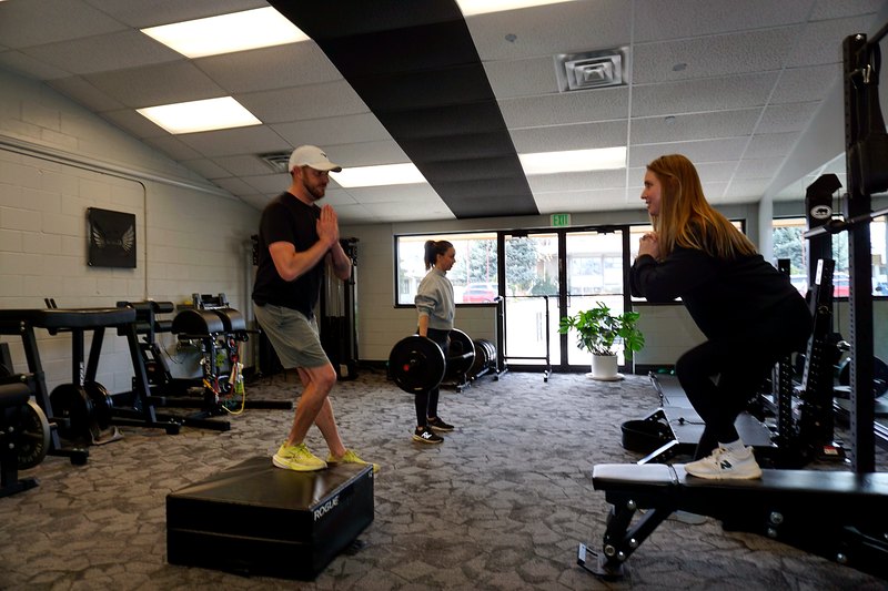 Omega coaching a client through a strength movement